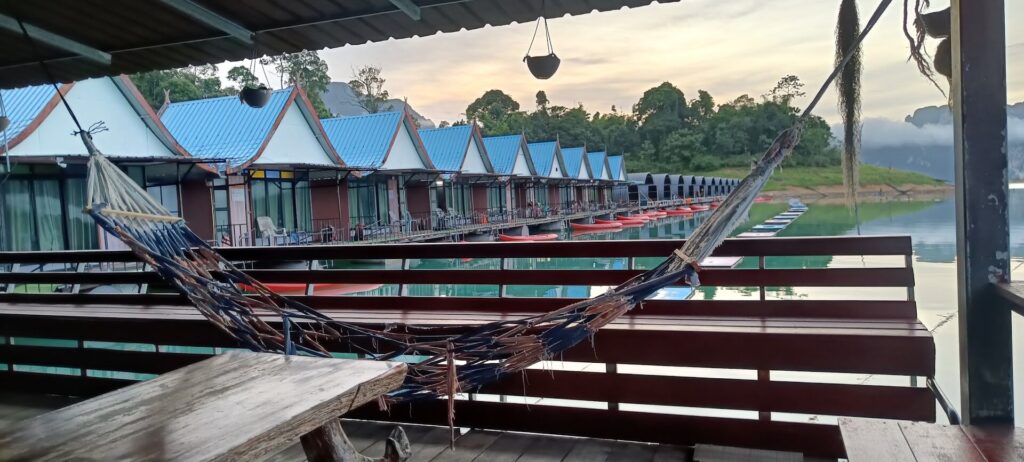 A hammock in the foreground, with Khao Sok Smiley Lakehouse bungalows in the background