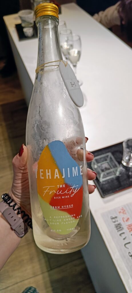 A hand holding a bottle of sake in a sake bar in Tokyo