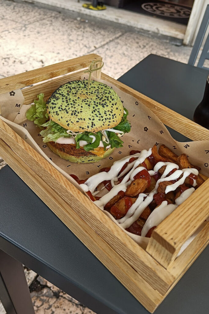 A burger and some fries served in a wooden crate in Flower Burger, a vegan Verona restaurant