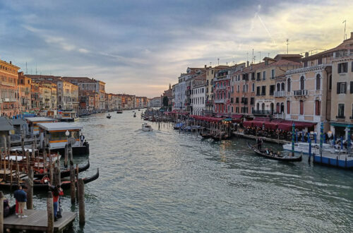 A wide canal winding through Venice, with buildings on either side. It's early evening and the sky has a golden glow.