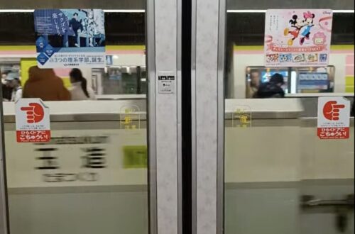 Train doors with advertisements and signage about Japanese train rules. Taken in a Tokyo metro train