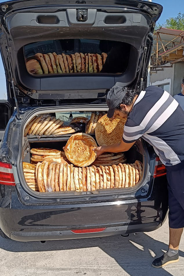 Uzbek man selling bread from the boot of a car