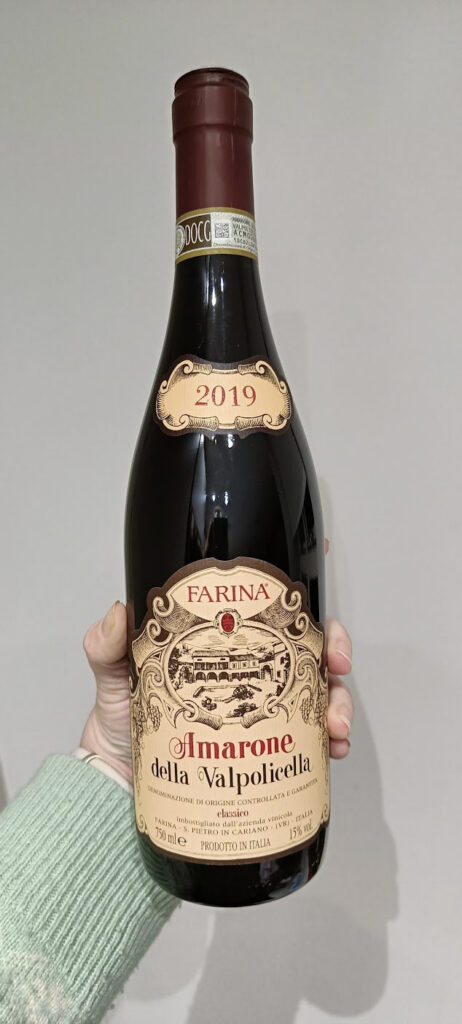 A hand holding a 2020 vintage of Farina Amarone
