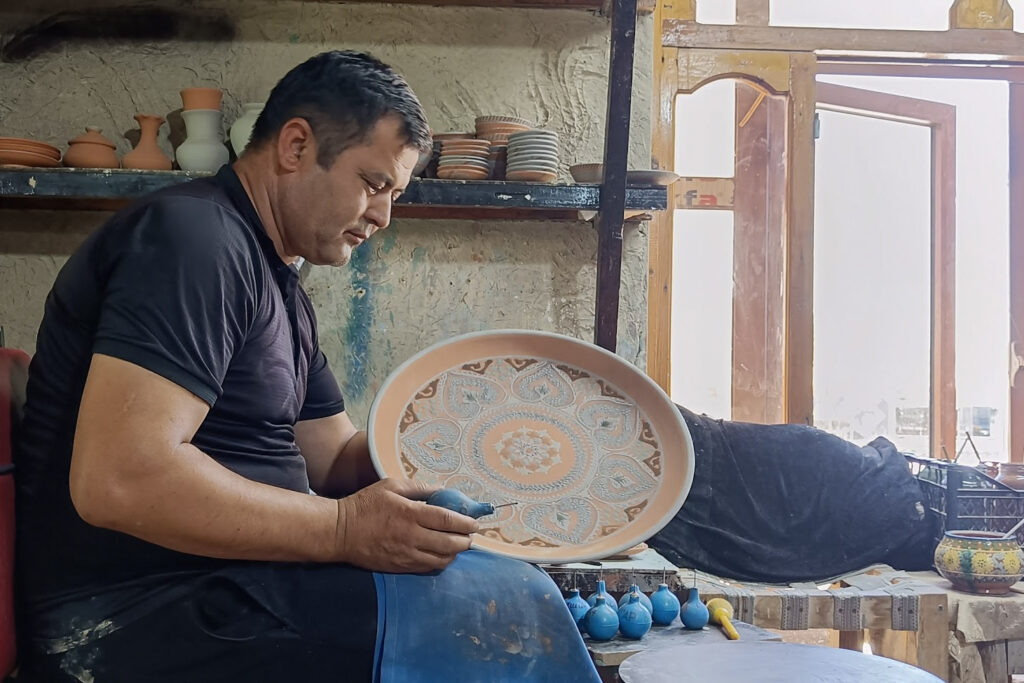 Potter crafting decorative clay plate at the Gijduvan Ceramics workshop in Bukhara