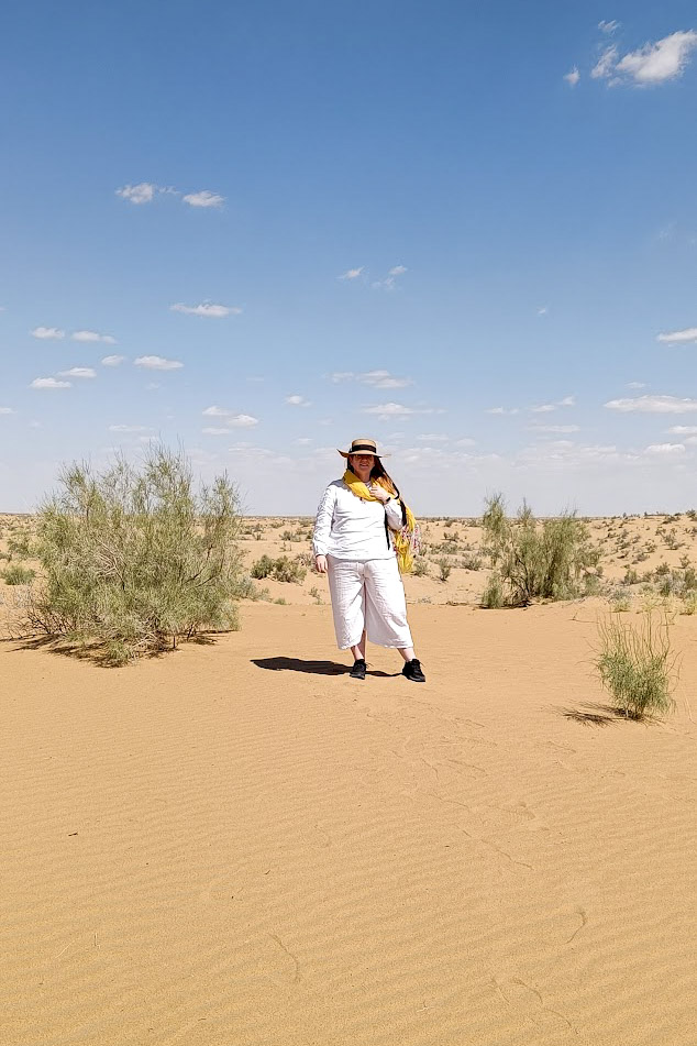 A woman wearing white standing in the Kyzylkum Desert in Uzbekistan